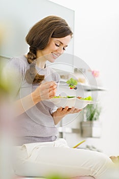 Woman eating fresh salad in kitchen
