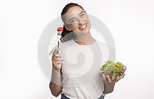 Woman Eating Fresh Vegetable Salad Standing In Studio, Isolated