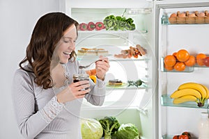 Woman Eating In Front Of Fridge