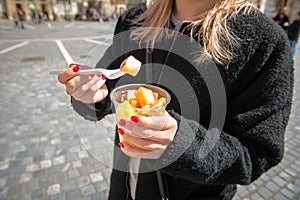 Woman eating fruit salad from lunch box in the city photo