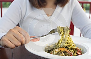 Woman eating green pesto sauce spaghetti.