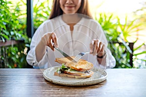 A woman eating ham cheese sandwich