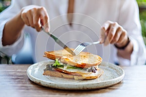 A woman eating ham cheese sandwich