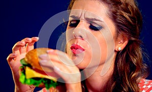 Woman eating hamburger. Appetizing face of girl happy eat junk .
