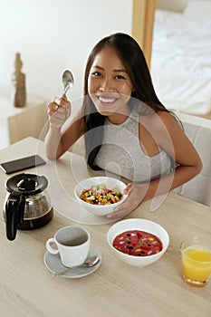 Woman eating healthy breakfast at home in morning at table