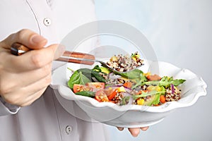 Woman eating healthy quinoa salad with vegetables from plate