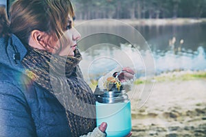 Woman is eating a hot dish from a thermos