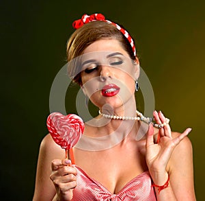 Woman eating lollipops. Girl in pin-up style hold striped candy.