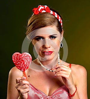 Woman eating lollipops. Girl in pin-up style hold striped candy.