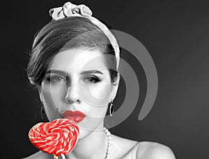 Woman eating lollipops. Girl in pin-up style hold striped candy.