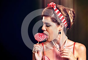 Woman eating lollipops. Girl in pin-up style hold striped candy.