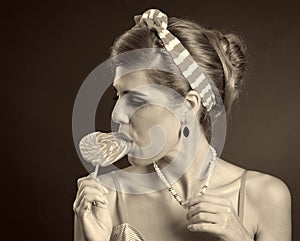 Woman eating lollipops. Girl in pin-up style hold striped candy.