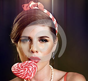 Woman eating lollipops. Girl in pin-up style hold striped candy.