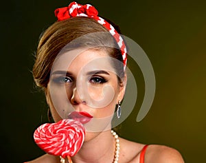 Woman eating lollipops. Girl in pin-up style hold striped candy.