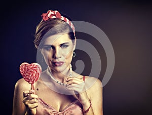 Woman eating lollipops. Girl in pin-up style hold striped candy.