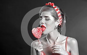 Woman eating lollipops. Girl in pin-up style hold striped candy.