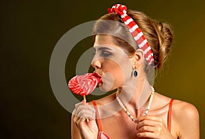 Woman eating lollipops. Girl in pin-up style hold striped candy.