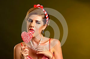 Woman eating lollipops. Girl in pin-up style hold striped candy.