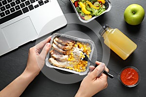 Woman eating from lunchbox at grey table. Healthy food delivery