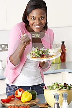 Woman Eating Meal In Kitchen