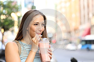 Woman eating a milkshake in the street