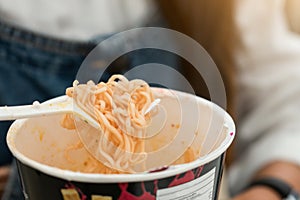 Woman eating noodles cup with a Plastic Fork