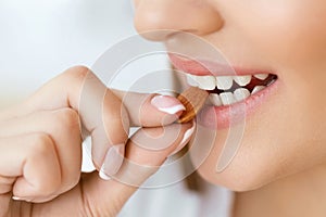 Woman Eating Nuts. Closeup Of Female Mouth Biting Nut.