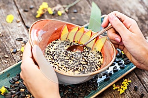 Woman eating oatmeal porridge sunflower seeds, sesame and peaches. Selective focus