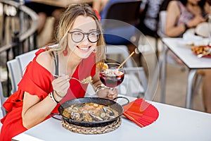 Woman eating Paella dish at the restaurant