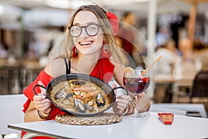 Woman eating Paella dish at the restaurant