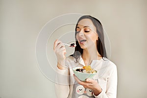 Woman eating porridge with fruits using spoon