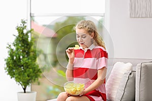 Woman eating potato chips in living room