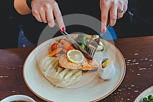 A woman eating redfish steak and mashed potatoes with vegetables