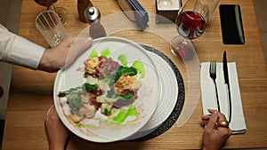 Woman eating restaurant food dinner. Waiter putting plate on table in cafe.