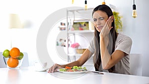 Woman eating salad, feeling tooth ache from excess acid in products, health