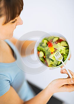 Woman eating salad with vegetables