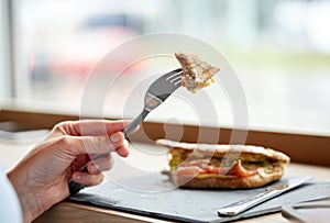 Woman eating salmon panini sandwich at restaurant