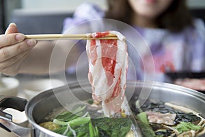 Woman is eating shabu shabu beef with hot pot