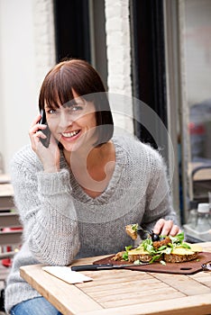 Woman eating and smiling with mobile phone