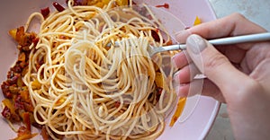 Woman eating spaghetti with vegetable sauce. Female hand holding fork with Italian pasta cooked of vegetarian recipe