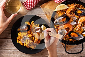 Woman eating spanish seafood paella on wooden table