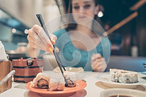 Woman eating sushi food in Japanese restaurant