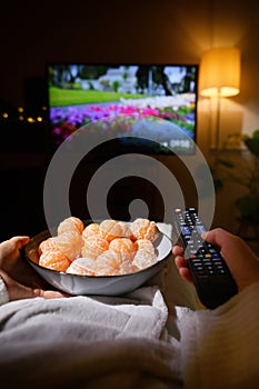 Woman Eating Tangrine And Watching TV On Bed