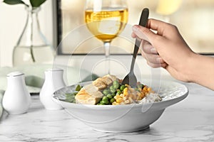 Woman eating tasty boiled rice with meat and vegetables at table