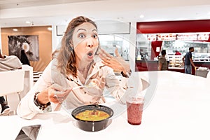 Woman eating too hot and peppery soup in an Asian fast food restaurant. Concept of spices in Oriental cuisine