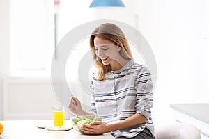 Woman eating vegetable salad in kitchen
