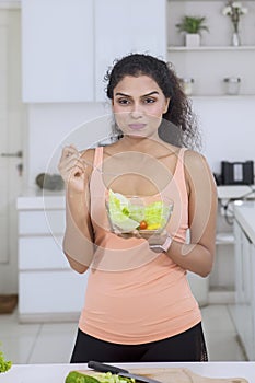 Woman eating vegetable salad in the kitchen