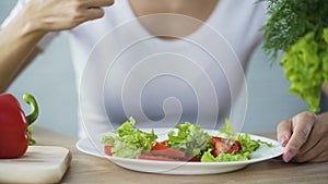 Woman eating vegetable salad, observing diet and counting calories, wellness