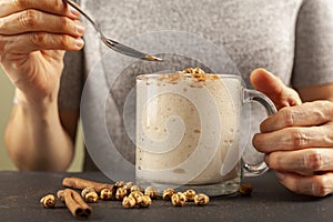 Woman eating a viscose malted barley, wheat beverage served in a cup with roasted chickpeas leblebi and cinnamon powder