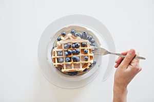 Woman eating waffles with blueberries for breakfast